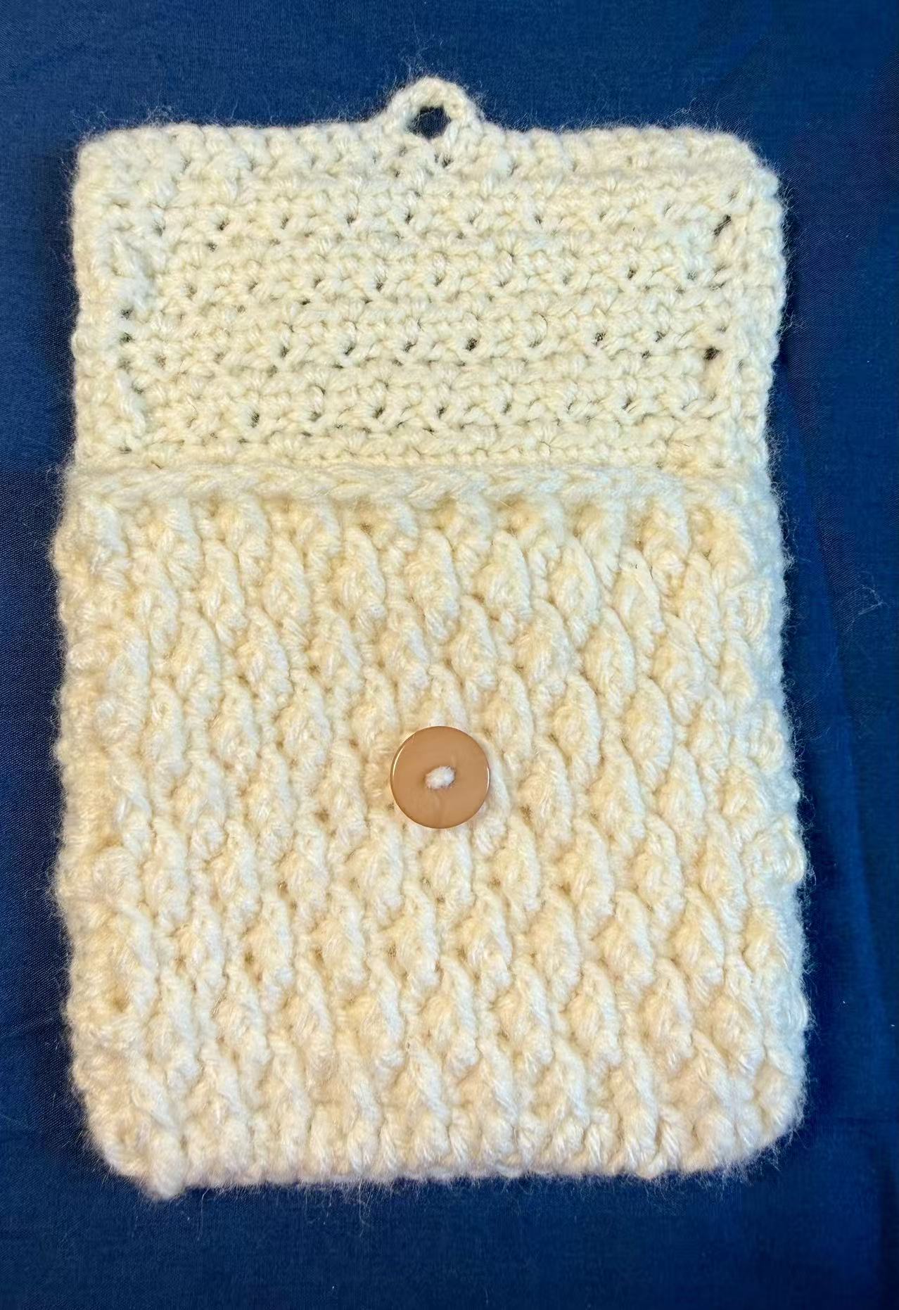 White crochet pouch shown open with the button loop released.
