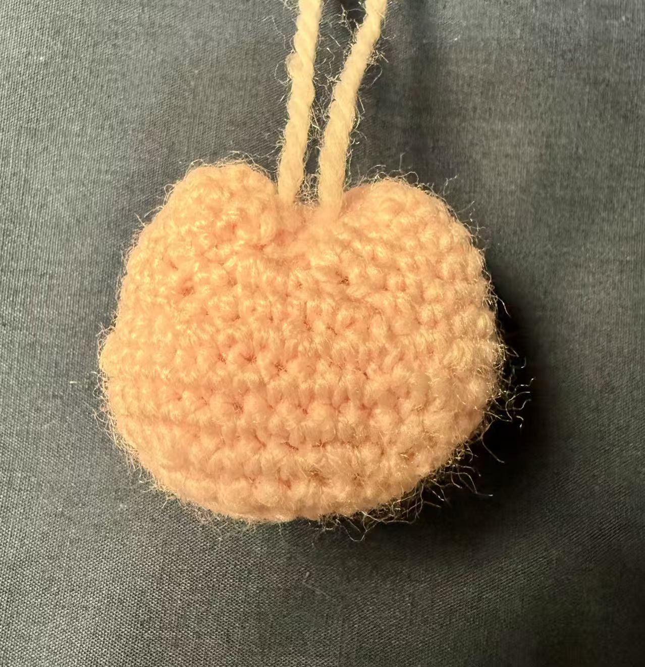 Back view of the light-pink crocheted cat keychain.