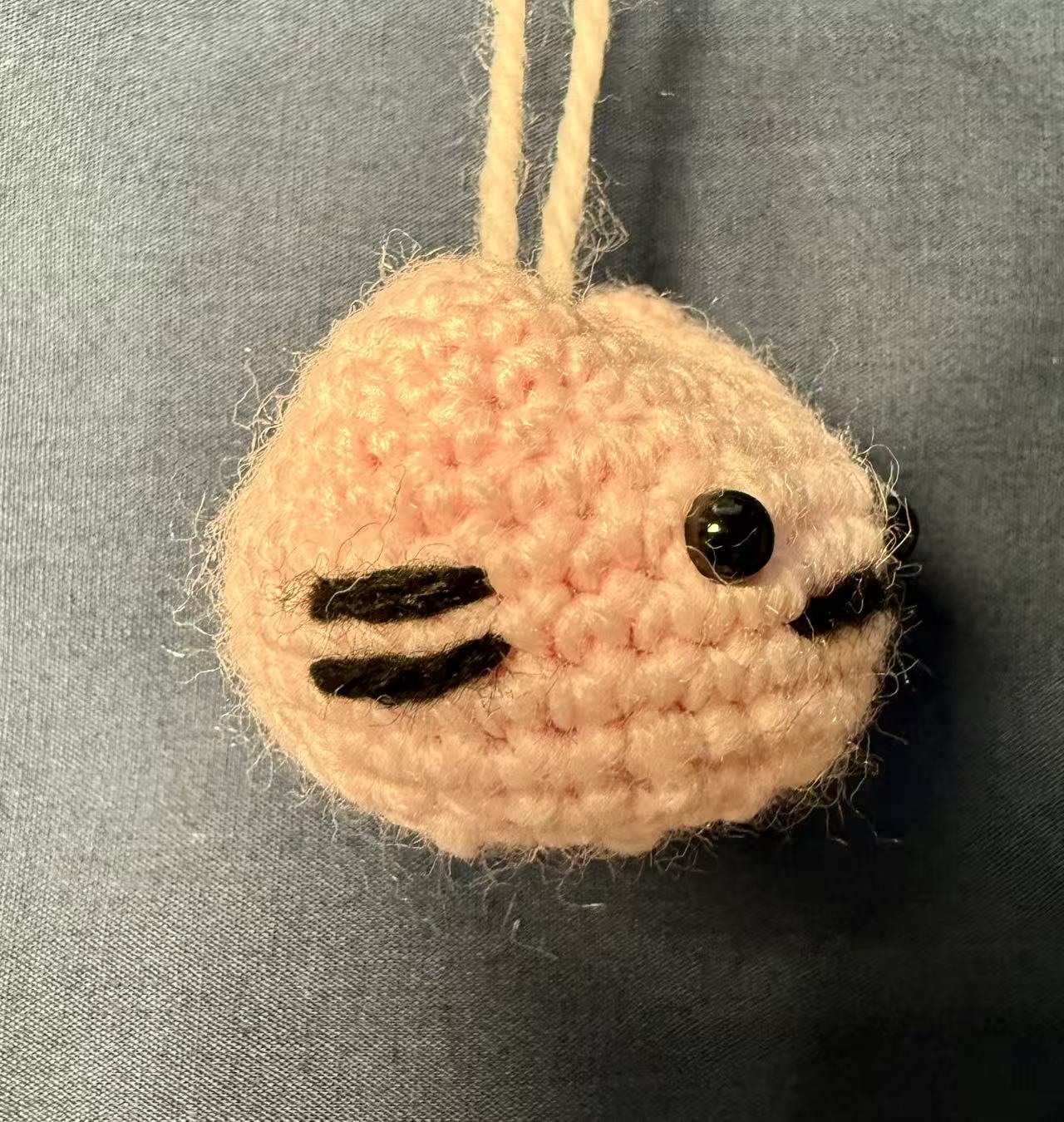 Left-side view of the light-pink crocheted cat keychain.