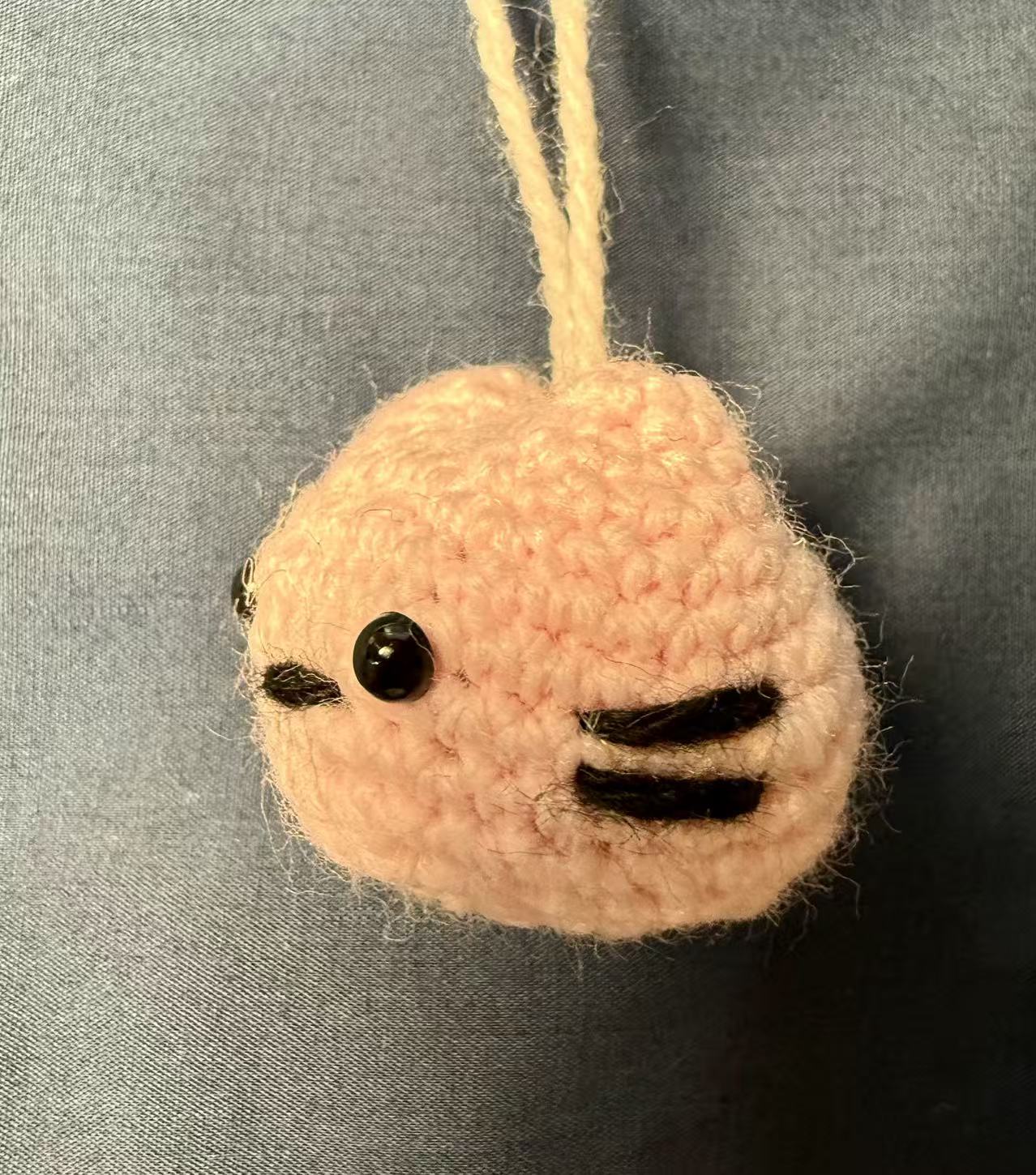 Right-side view of the light-pink crocheted cat keychain.