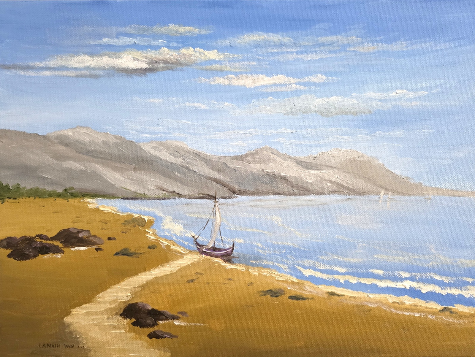 Coastal landscape with golden sand, blue water, distant gray mountains, and small sailboats beneath a pale blue sky.